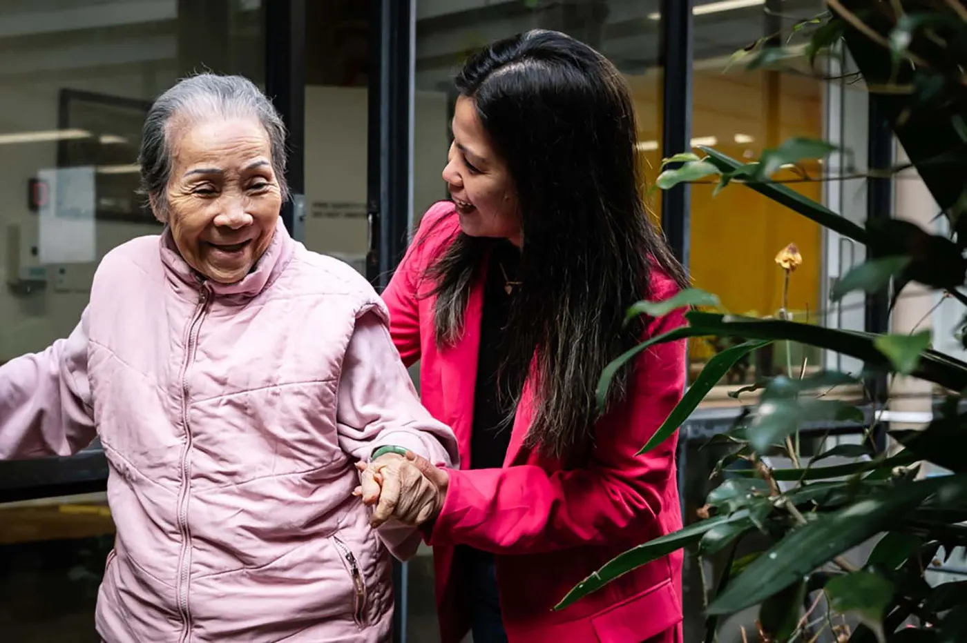 A resident and carer laughing together in the courtyard at Nexia Aged Care Footscray