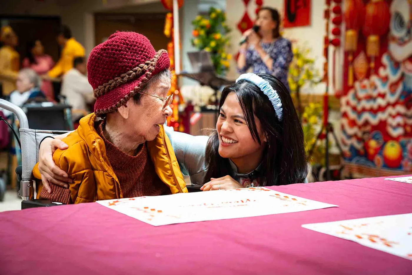 A resident and team member sharing a laugh at the Lunar New Year celebration at Nexia Aged Care Footscray